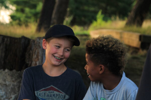 Two boys giggling together outside.
