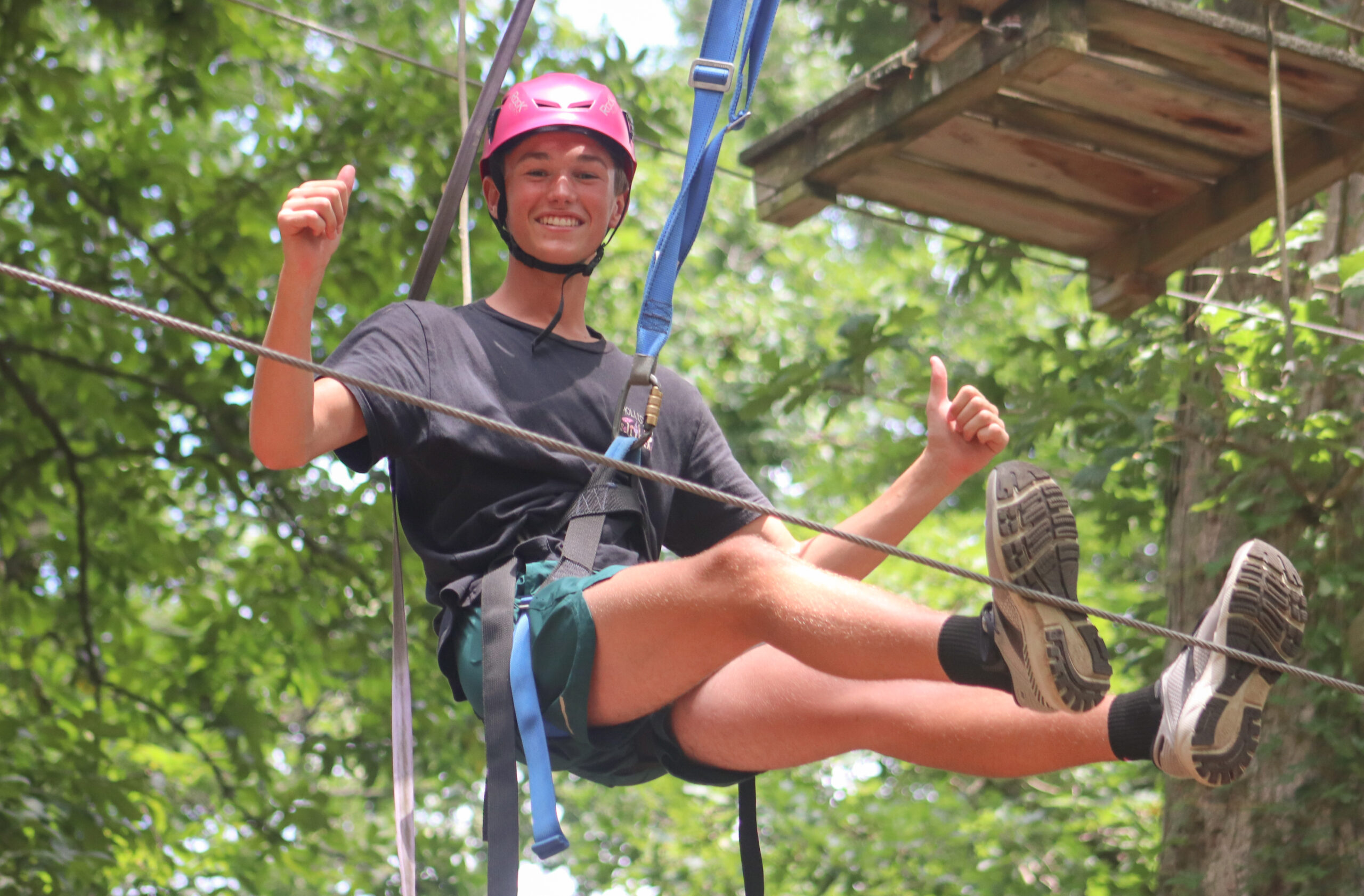 Image of a boy hanging out on the high ropes course.