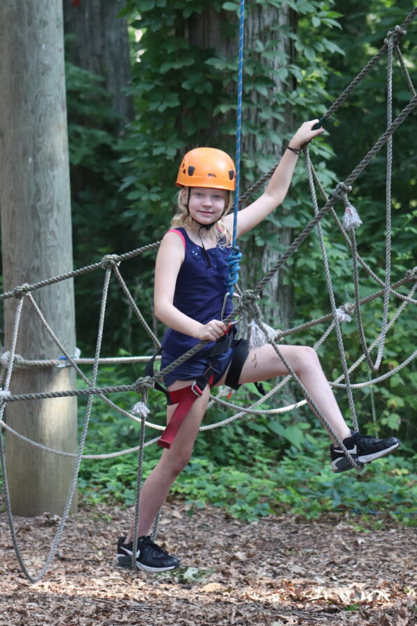 Image of a young girl doing the high ropes course.