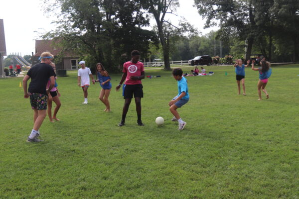 Image of several boys and girls playing soccer in the rec field.