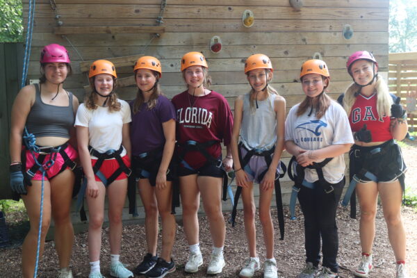 image of several girls preparing to do the rock climbing tower.