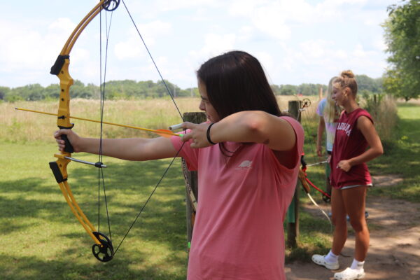 image of girls practicing archery outdoors.