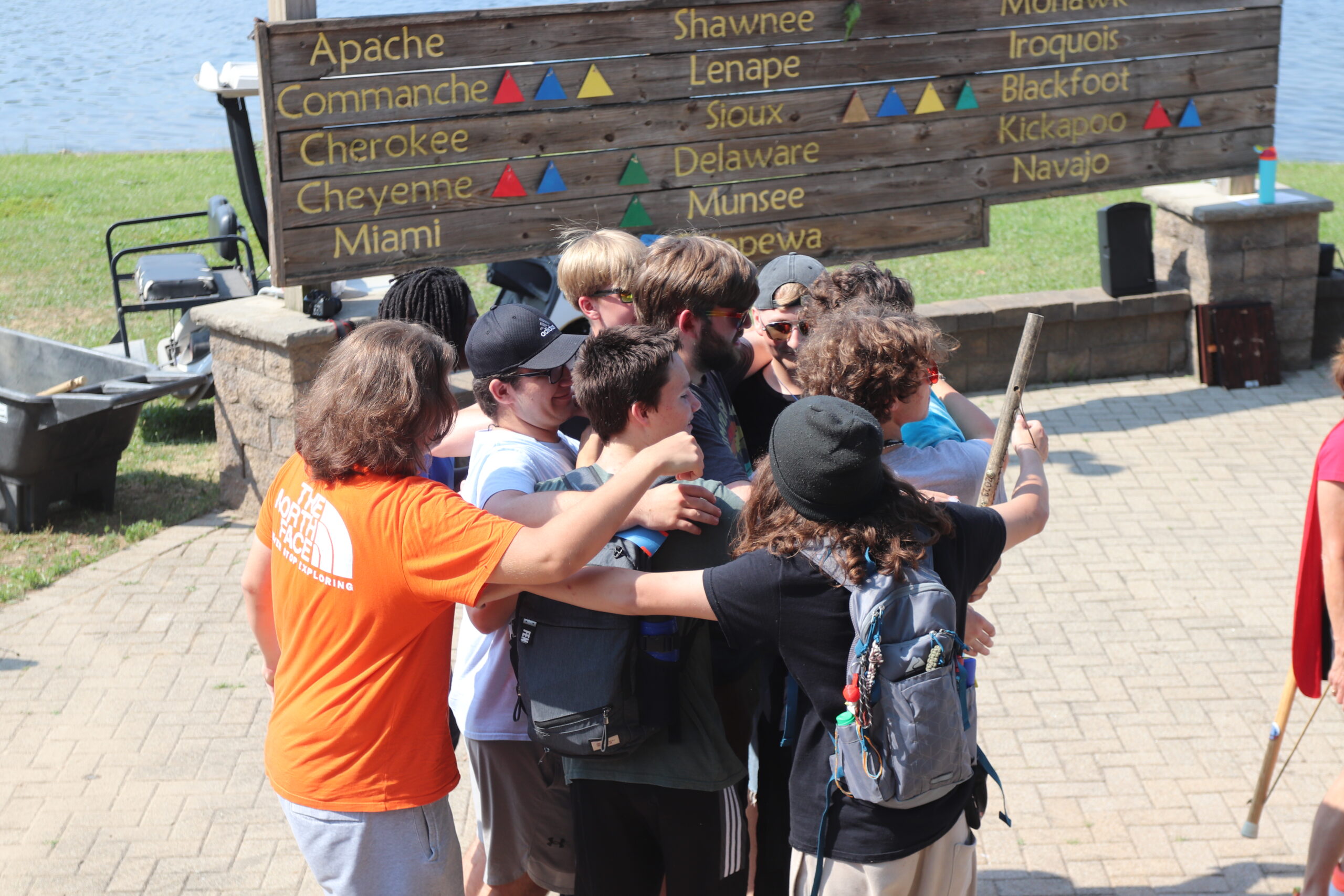 A group of boys huddling together in front of Lake Tippecanoe.
