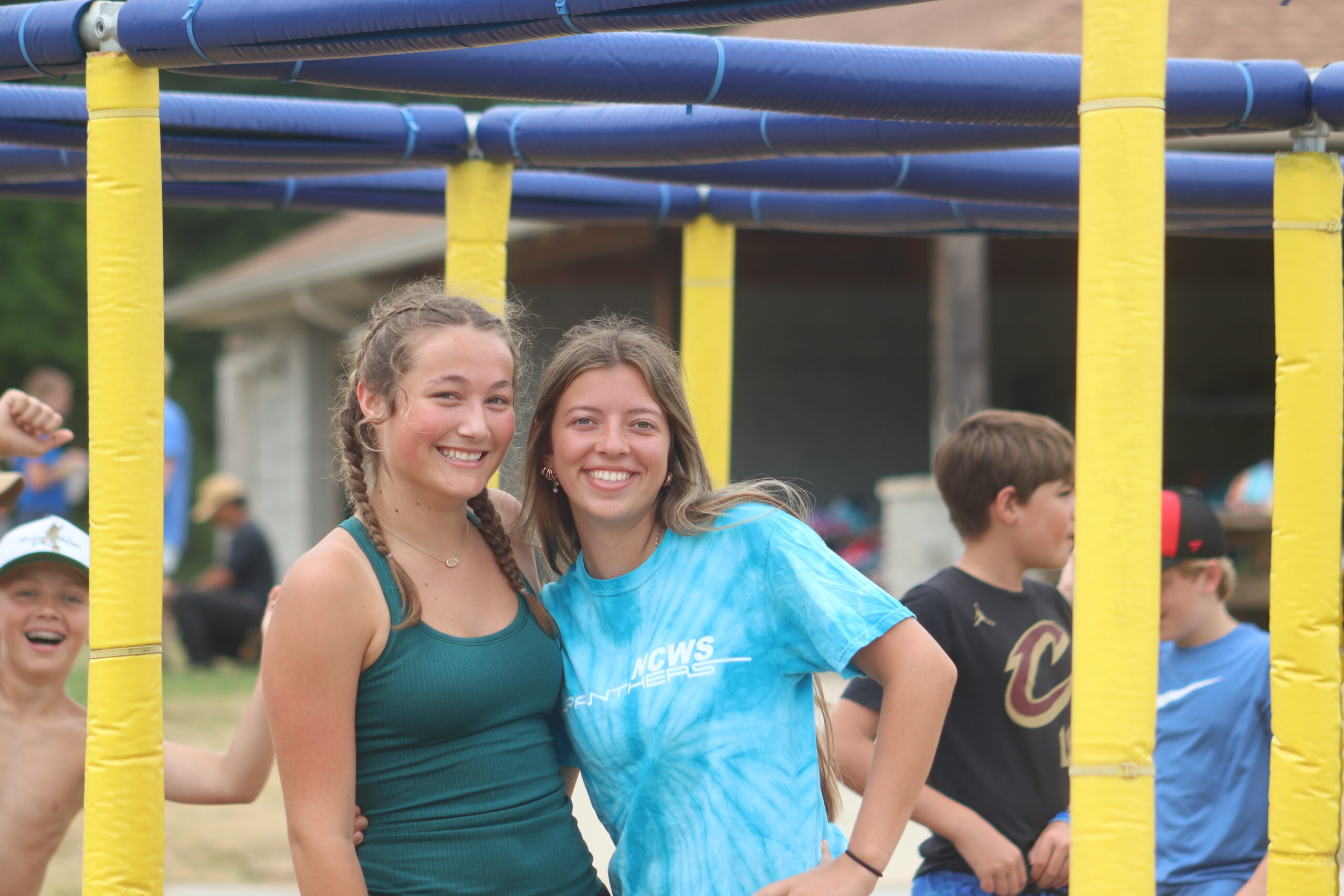 Two girls posing for a photo together in front of the nine square court.