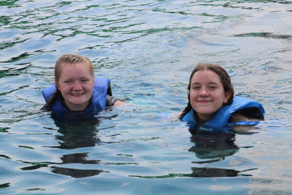 Two girls swimming in the H2O Woah Zone with life jackets on.